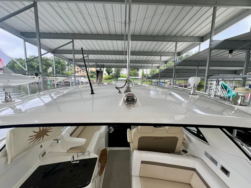 Slide: The Image of 2014 Sea Ray 410 Sundancer yacht interior under covered dock, featuring seating and helm area. - 38