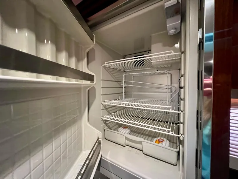 Slide: The Image of Empty refrigerator inside 2014 Sea Ray 410 Sundancer yacht, featuring wire shelves and door storage. - 42