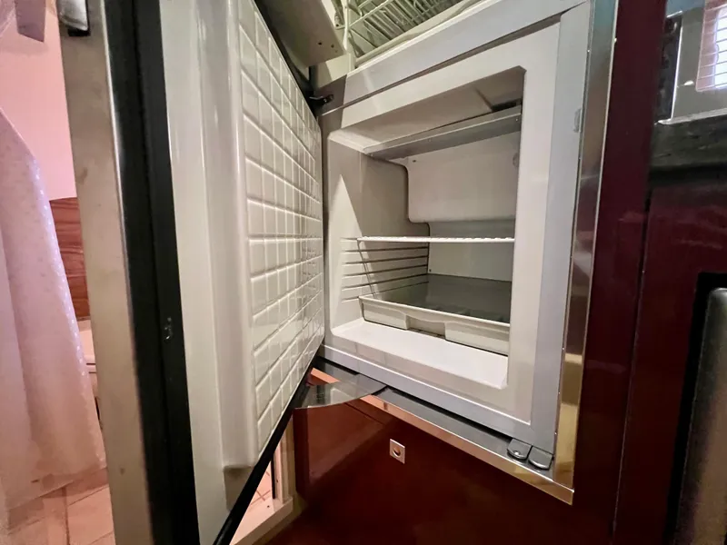 Slide: The Image of Open refrigerator inside 2014 Sea Ray 410 Sundancer yacht, showcasing interior storage space. - 43