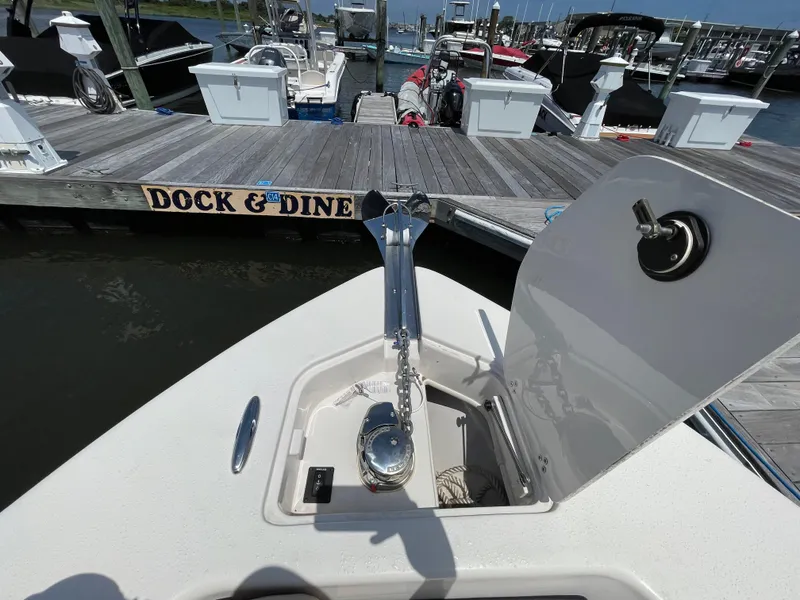 Slide: The Image of 2023 Sea Chaser 24 HFC boat at dock, anchor compartment open, "Dock & Dine" sign visible. - 10