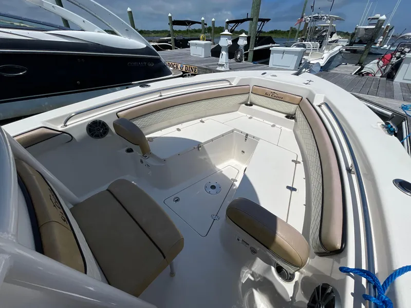 Slide: The Image of 2023 Sea Chaser 24 HFC boat interior with cushioned seating at a marina. - 13