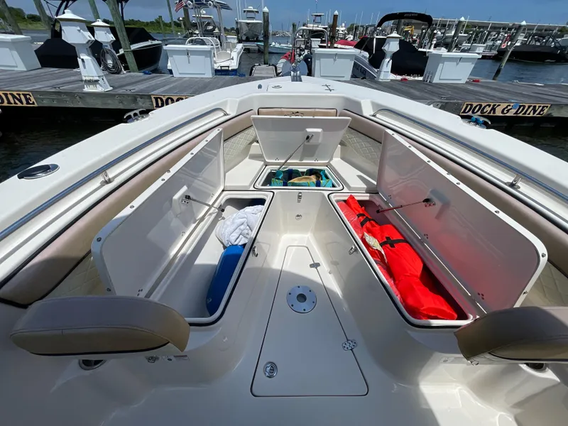 Slide: The Image of 2023 Sea Chaser 24 HFC boat with open storage compartments at a marina. - 15