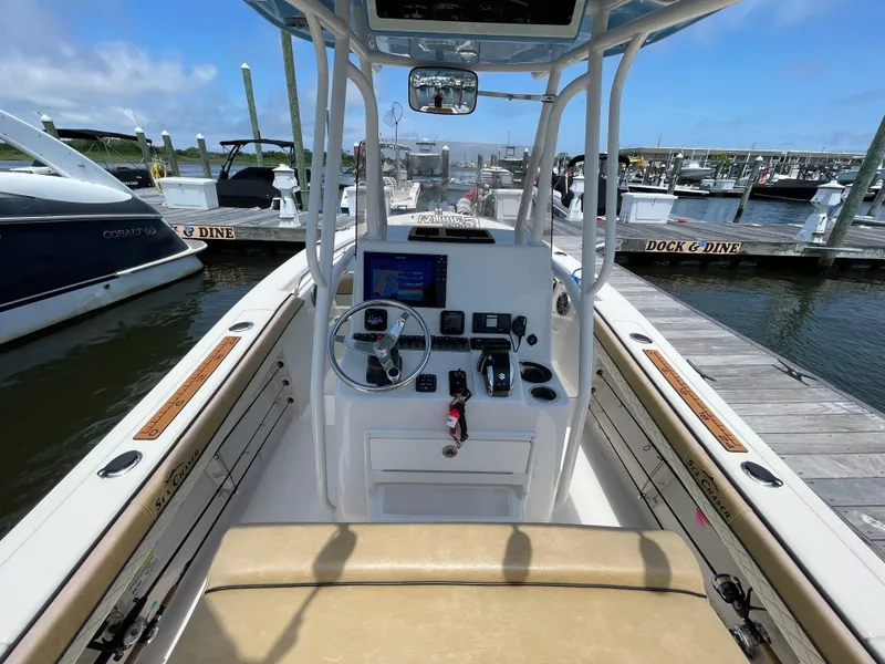 Slide: The Image of 2023 Sea Chaser 24 HFC boat interior at marina, featuring steering console and seating. - 25