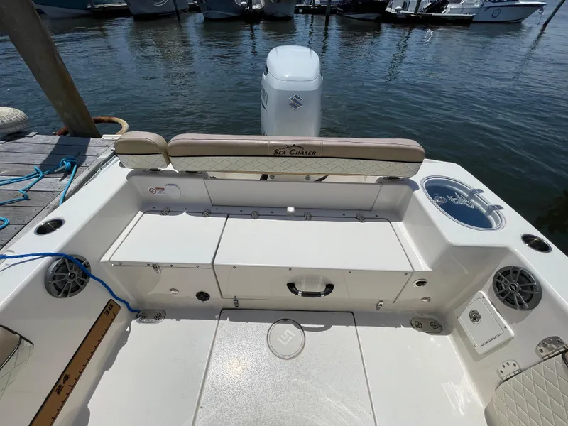 Slide: The Image of 2023 Sea Chaser 24 HFC boat interior with seating and storage, docked by the water. - 38