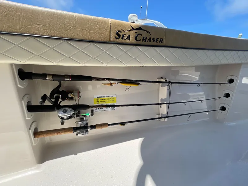 Slide: The Image of Fishing rods stored on a 2023 Sea Chaser 24 HFC boat under clear blue skies. - 45