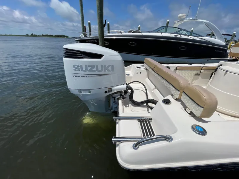 Slide: The Image of 2023 Sea Chaser 24 HFC with Suzuki outboard motor docked on calm water. - 48