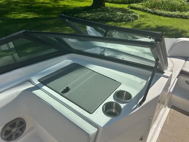 Slide: The Image of 2020 Sea Ray SPX 210 boat interior with windshield and cup holders, set in a grassy area. - 25