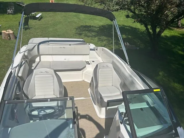 Slide: The Image of 2020 Sea Ray SPX 210 boat interior with seating and canopy, parked on grass. - 27