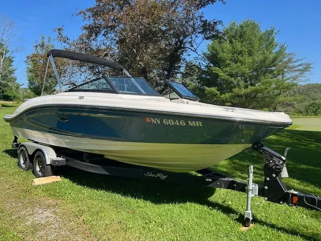 Slide: The Image of 2020 Sea Ray SPX 210 boat on trailer, parked on grass with trees in background. - 30