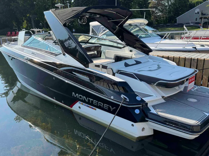 Slide: The Image of 2017 Monterey 328 Super Sport boat docked, sleek design, black and white exterior. - 2