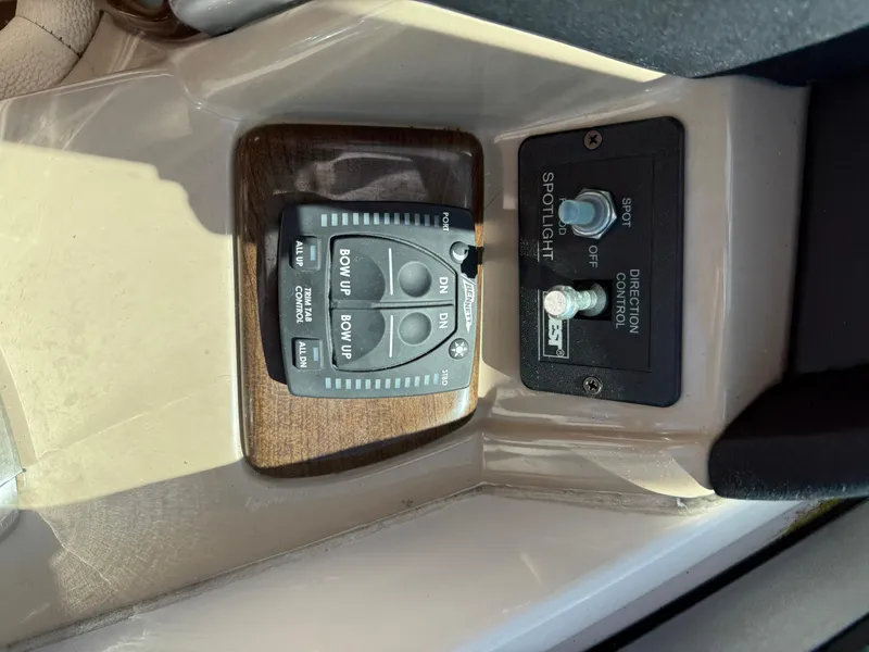 Slide: The Image of 2008 Four Winns V358 boat controls, featuring trim tab and spotlight direction switches. - 16