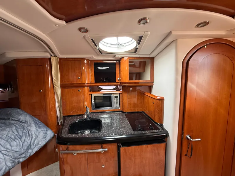 Slide: The Image of 2008 Four Winns V358 yacht interior with kitchenette, featuring wood cabinetry, sink, and appliances. - 20