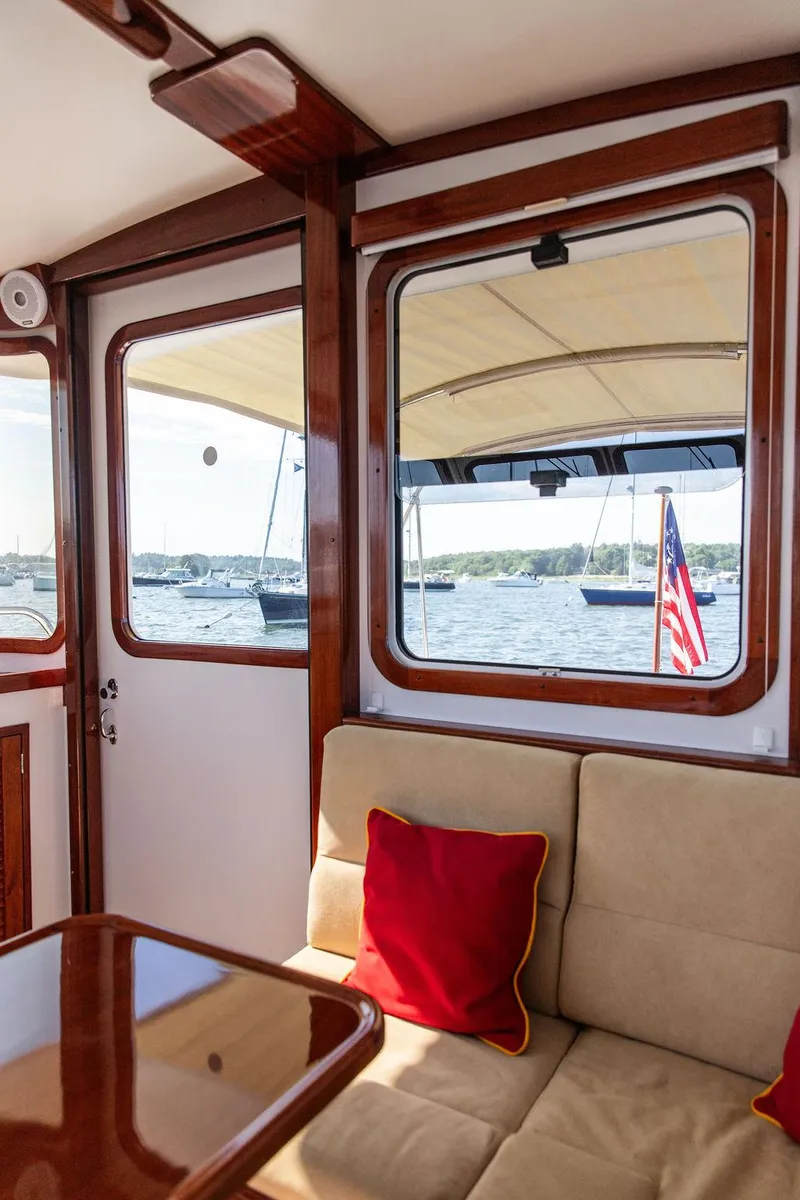 Slide: The Image of Interior of 2014 Bruckmann Abaco 40 yacht with beige seating, red cushions, and window view of marina. - 31