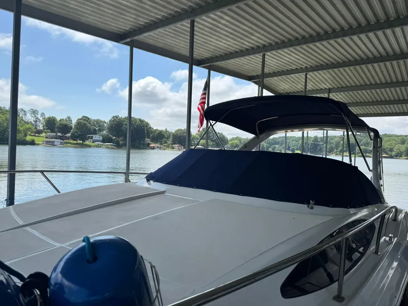 Slide: The Image of 2006 Regal 3360 Window Express boat docked under a covered marina with scenic lake view. - 10