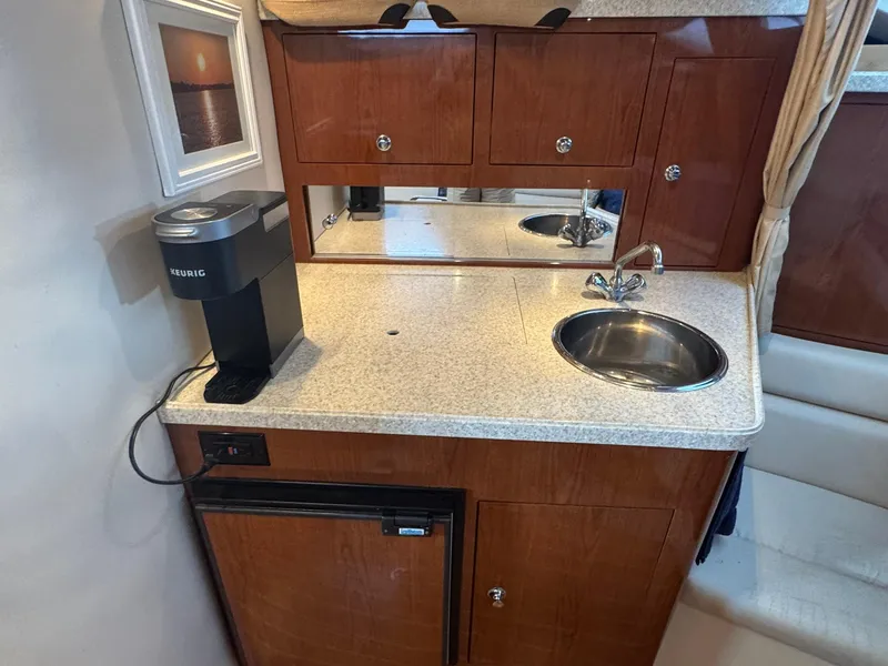 Slide: The Image of 2006 Regal 3360 Window Express yacht kitchenette with sink, Keurig coffee maker, and wooden cabinets. - 24