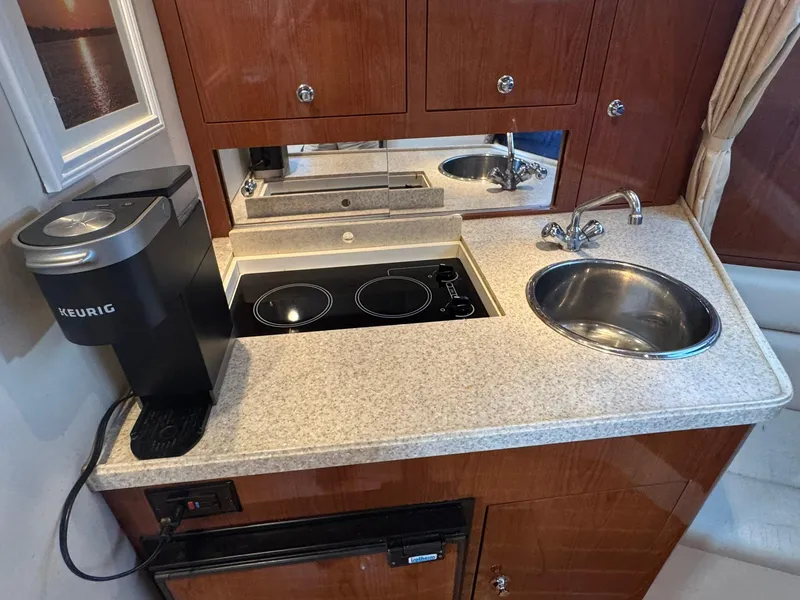 Slide: The Image of Compact kitchen area in a 2006 Regal 3360 Window Express boat with sink and Keurig coffee maker. - 26