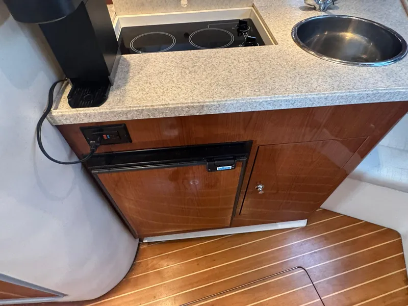 Slide: The Image of 2006 Regal 3360 Window Express yacht kitchen with stove, sink, and wooden cabinetry. - 27