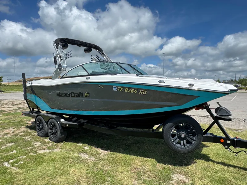 Slide: The Image of 2019 MasterCraft XT22 boat on trailer under a partly cloudy sky. - 11