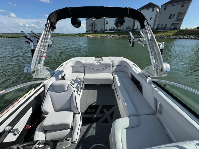Slide: The Image of 2019 MasterCraft XT22 boat interior with sleek seating on a calm lake. - 15