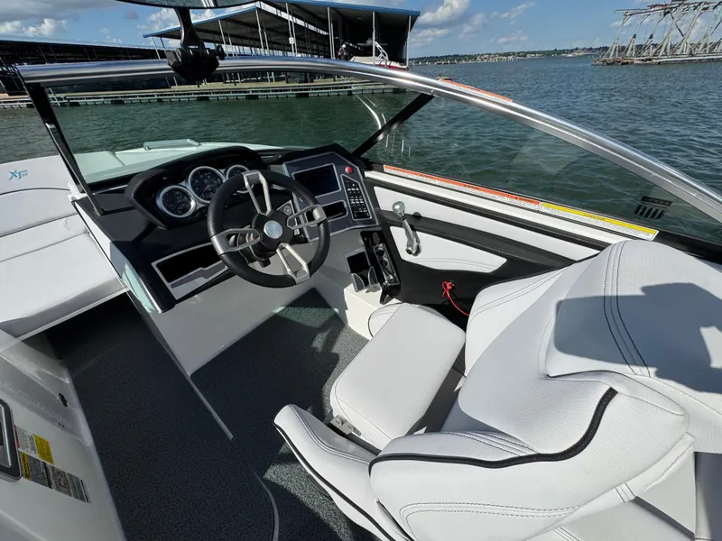 Slide: The Image of 2019 MasterCraft XT22 boat interior with steering wheel and dashboard, docked by the water. - 16