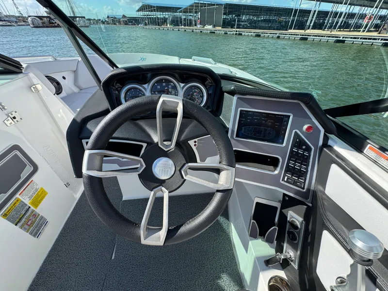 Slide: The Image of 2019 MasterCraft XT22 boat dashboard with steering wheel and control panel on a sunny day. - 17