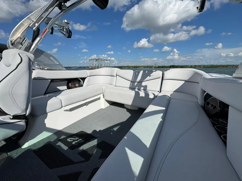 Slide: The Image of 2019 MasterCraft XT22 boat interior with white seating under a blue sky. - 19