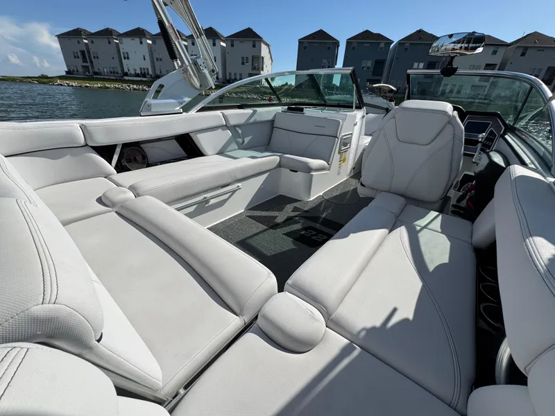 Slide: The Image of 2019 MasterCraft XT22 boat interior with white seating, docked near waterfront homes. - 23