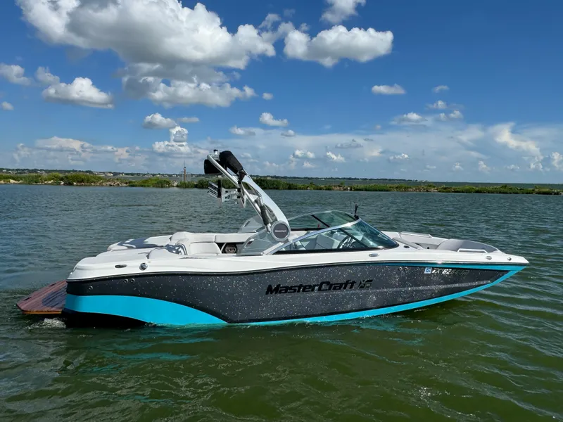 Slide: The Image of 2019 MasterCraft XT22 boat on a lake under a clear blue sky. - 5