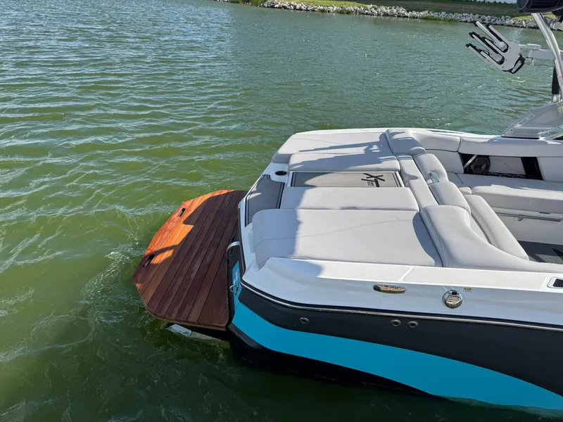Slide: The Image of 2019 MasterCraft XT22 boat with sleek seating and swim platform on a sunny lake. - 8