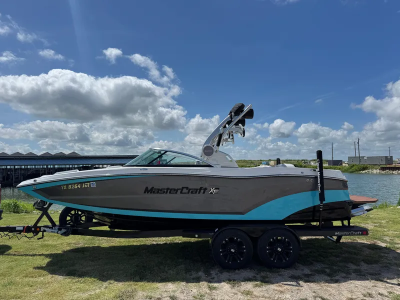 Slide: The Image of 2019 MasterCraft XT22 boat on trailer by a lake under a blue sky. - 9
