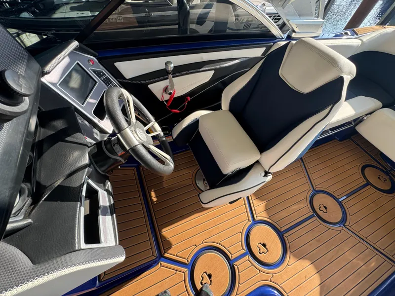 Slide: The Image of 2021 MasterCraft XT23 boat interior with steering wheel, control panel, and luxury seating. - 15