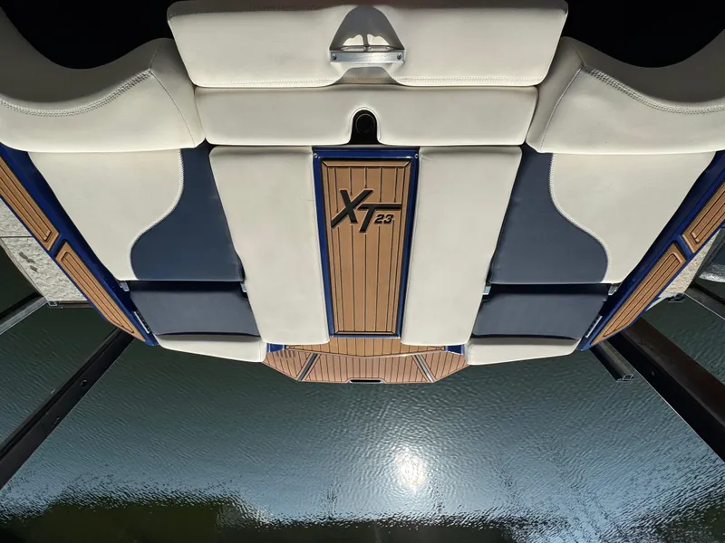 Slide: The Image of 2021 MasterCraft XT23 boat interior with stylish seating and wood accents on water. - 22