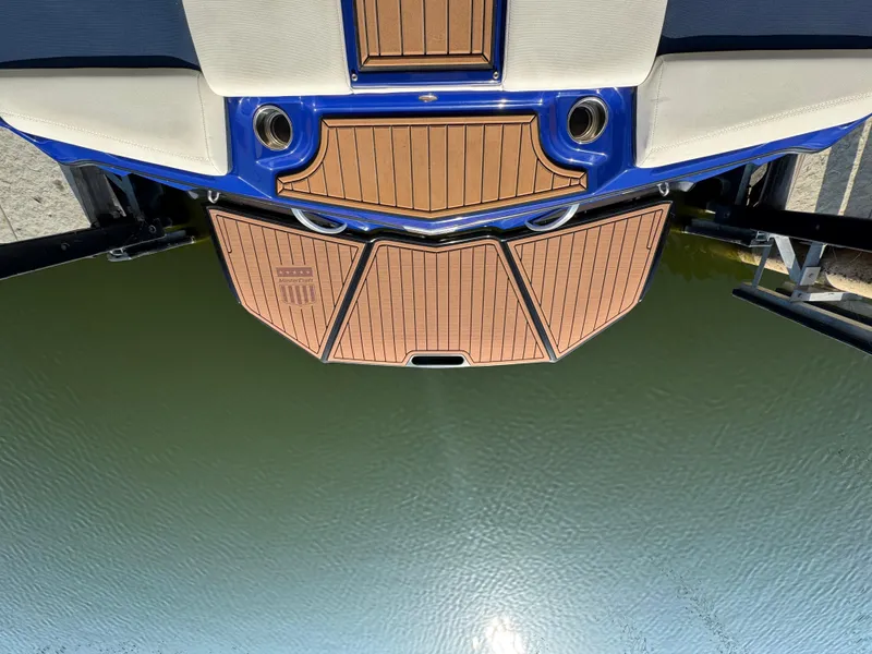 Slide: The Image of 2021 MasterCraft XT23 boat stern with teak deck, docked on calm water. - 23
