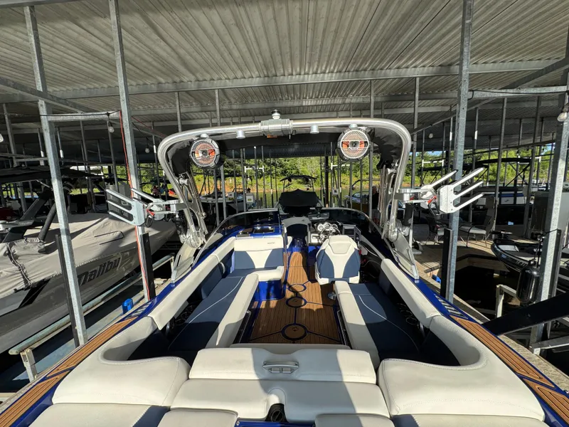 Slide: The Image of 2021 MasterCraft XT23 boat interior with seating and speakers, docked under a metal roof. - 24