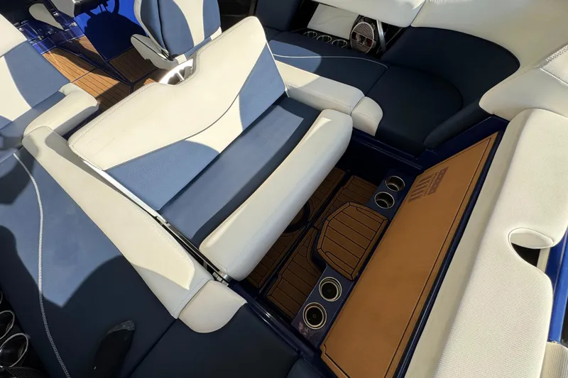 Slide: The Image of 2021 MasterCraft XT23 interior with blue and white seating, cup holders, and teak-style flooring. - 25