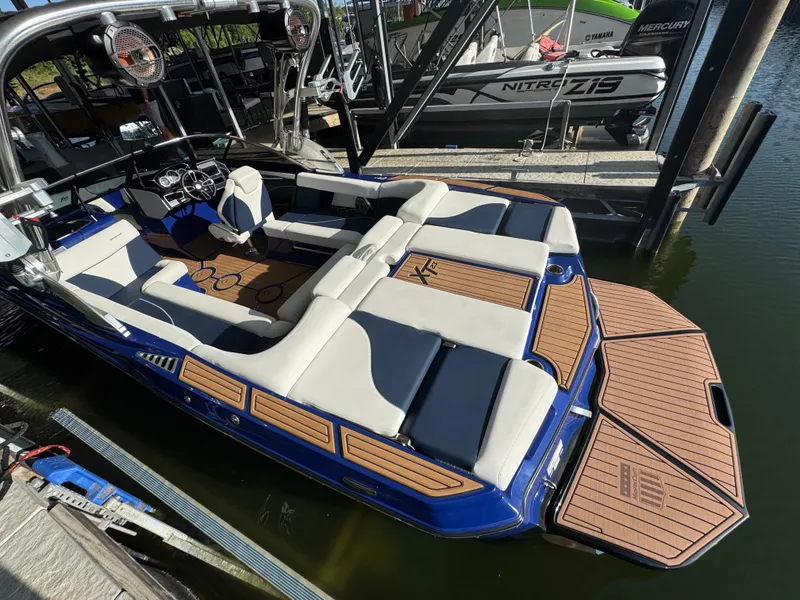 Slide: The Image of 2021 MasterCraft XT23 boat with spacious seating and sleek design docked by the water. - 8