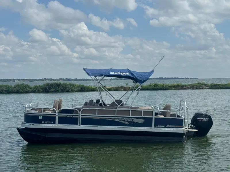 Slide: The Image of 2021 Ranger Reata 200F pontoon boat on a lake under a cloudy sky. - 1