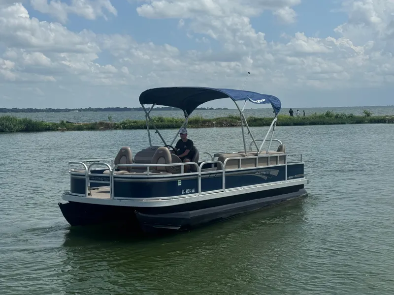 Slide: The Image of 2021 Ranger Reata 200F pontoon boat on a lake under a cloudy sky. - 2
