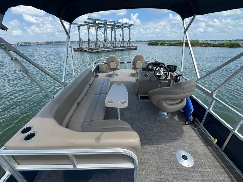 Slide: The Image of 2021 Ranger Reata 200F pontoon boat interior with seating and steering console on a lake. - 20