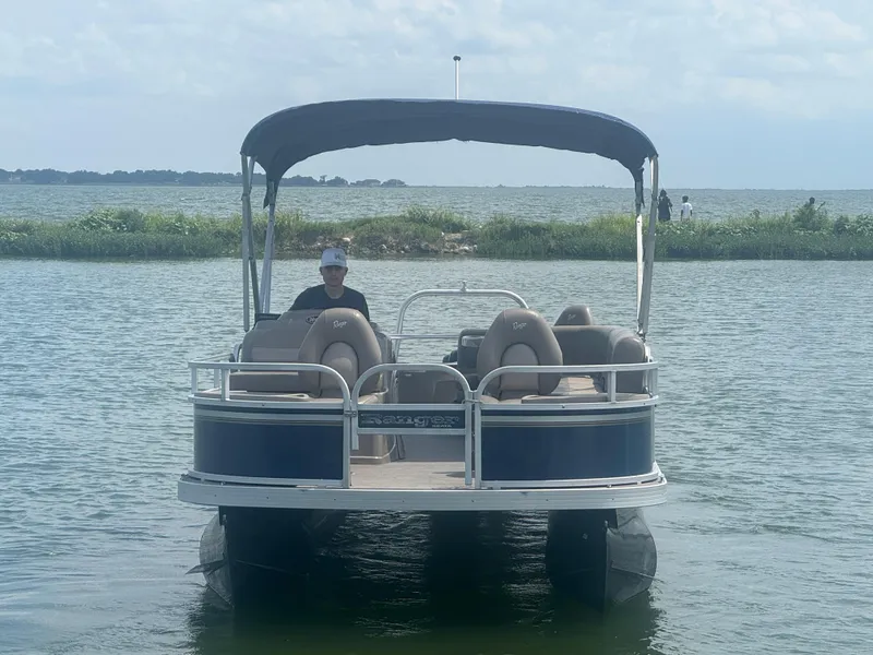 Slide: The Image of 2021 Ranger Reata 200F pontoon boat on a calm lake with canopy. - 3