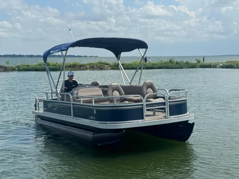 Slide: The Image of 2021 Ranger Reata 200F pontoon boat on a calm lake under a cloudy sky. - 4