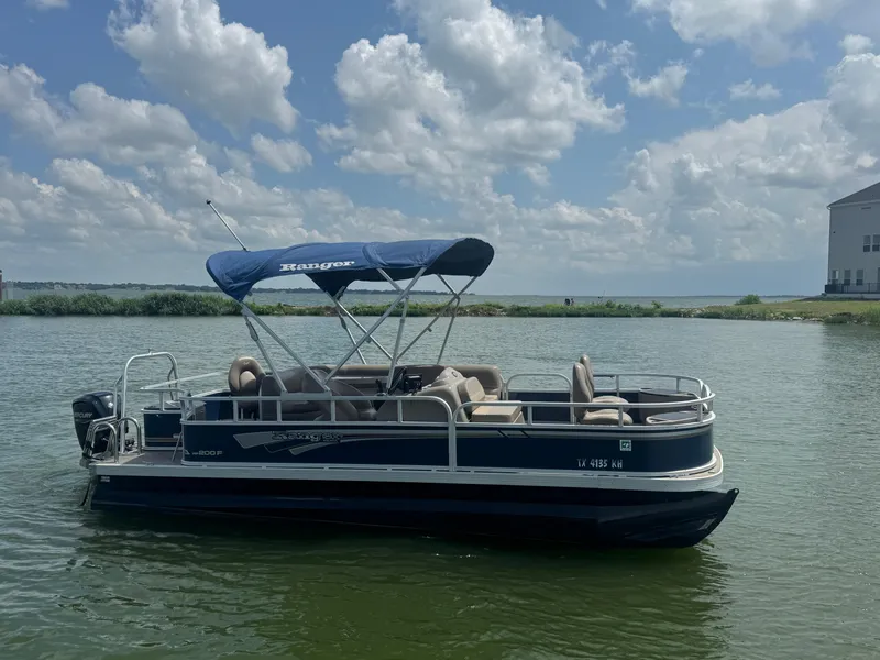 Slide: The Image of 2021 Ranger Reata 200F pontoon boat on a calm lake under a cloudy sky. - 5