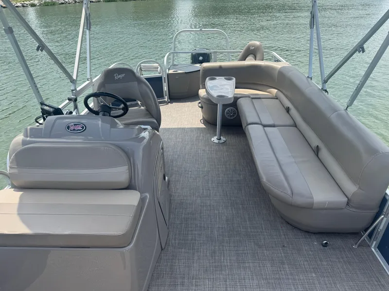 Slide: The Image of 2021 Ranger Reata 200F pontoon boat interior with seating and steering console on water. - 9