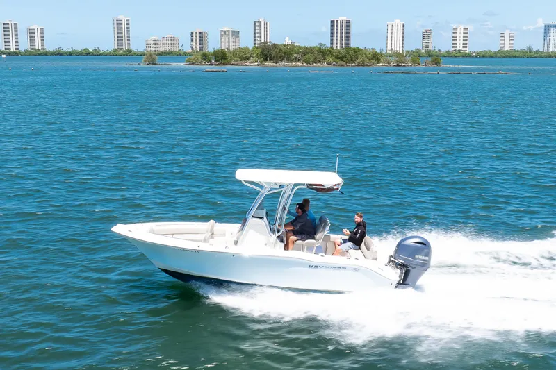 Slide: The Image of 2021 Key West 219 FS boat cruising on blue water with city skyline in background. - 11