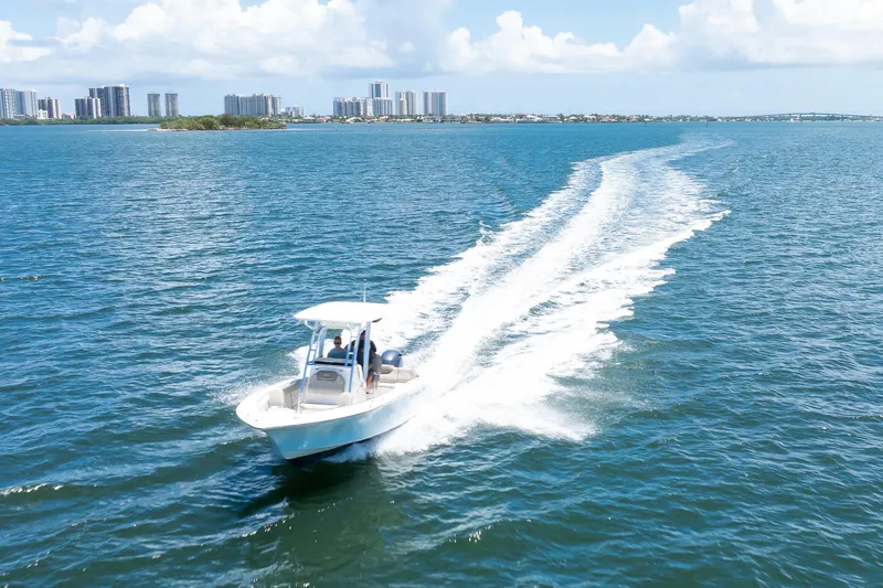 Slide: The Image of 2021 Key West 219 FS boat cruising on open water with city skyline backdrop. - 14