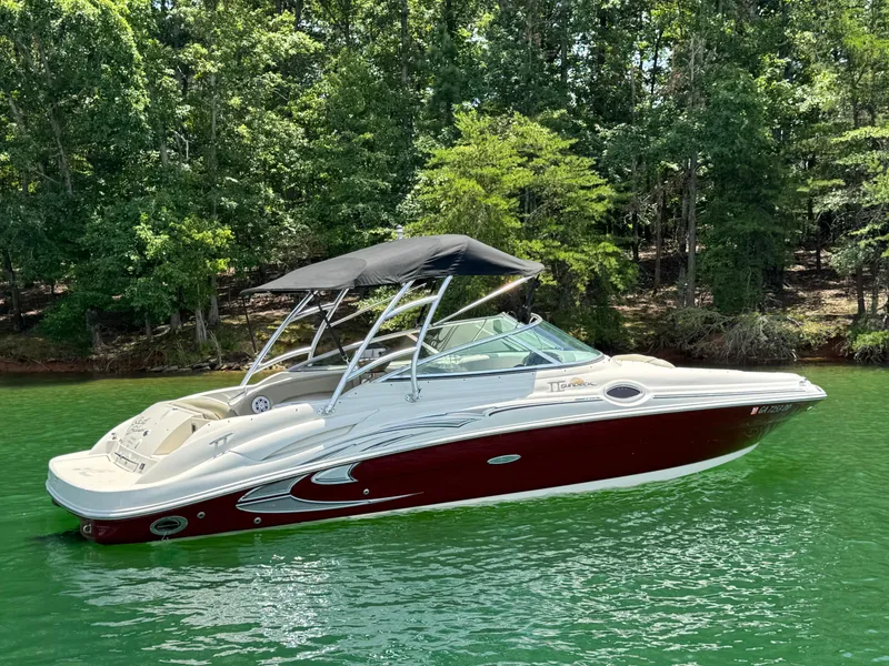 Slide: The Image of 2006 Sea Ray 270 Sundeck boat on a serene lake with lush green forest backdrop. - 10