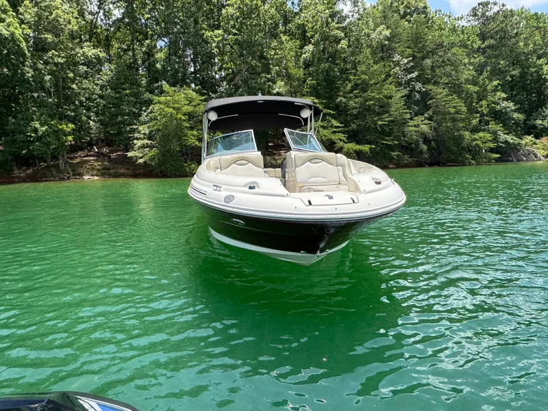 Slide: The Image of 2006 Sea Ray 270 Sundeck boat on a serene green lake, surrounded by lush trees. - 19