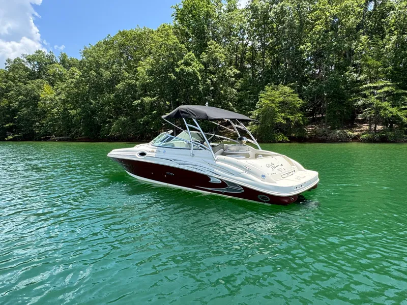 Slide: The Image of 2006 Sea Ray 270 Sundeck boat on a serene lake with lush green trees. - 2