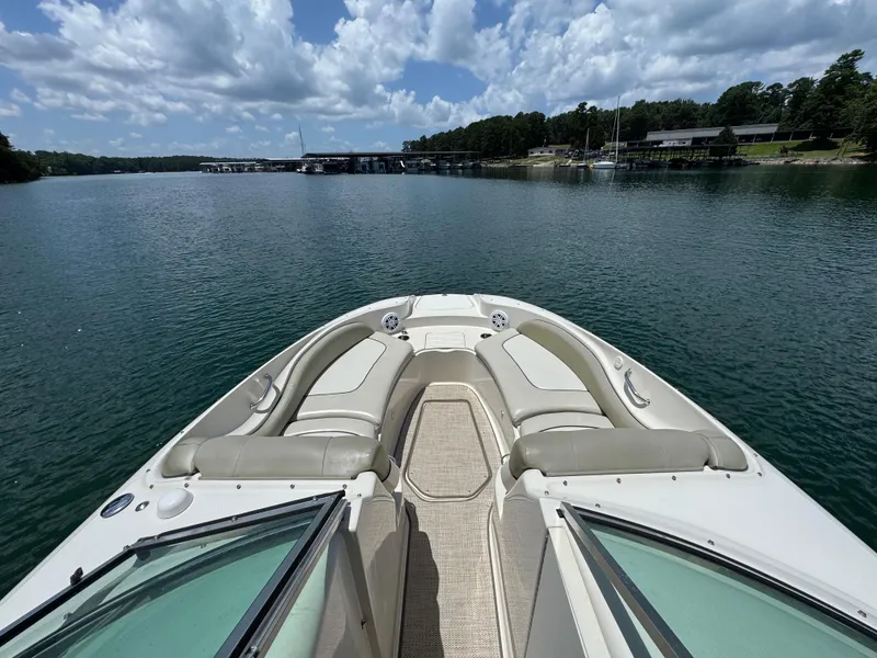 Slide: The Image of 2006 Sea Ray 270 Sundeck boat on a serene lake under a partly cloudy sky. - 27