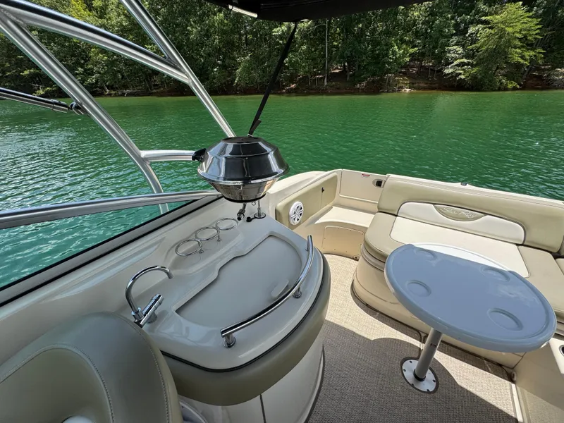Slide: The Image of 2006 Sea Ray 270 Sundeck interior with seating and table, overlooking a serene lake. - 32
